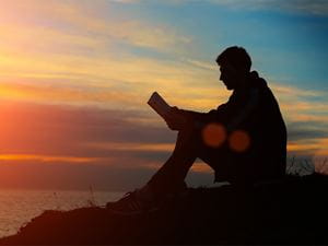 man reading the bible at sunset