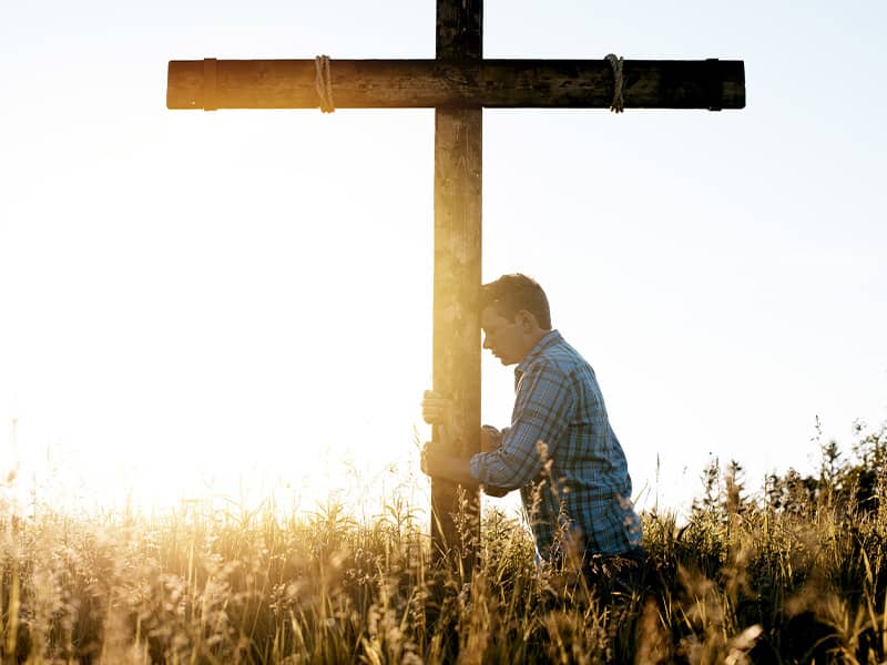 man praying at the foot of the cross