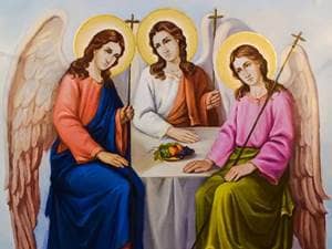 three angels sitting side by side with wings on their backs and halos of light around their heads