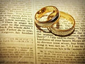 a pair of wedding rings stacked atop an open Bible