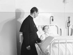 priest at a boy's hospital bed