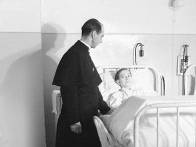 priest at a boy's hospital bed