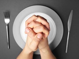 praying hands over empty plate