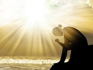 Woman praying by ocean