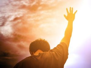 Man reaching up to colorful sky