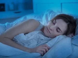 woman laying on her side sleeping on her bed