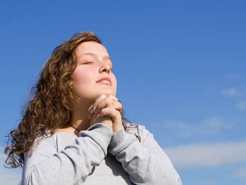 Woman praying against blue sky