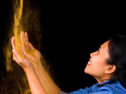 Gold dust pouring onto woman's hands
