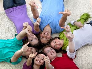 Kids lying down in the sand with thumbs up