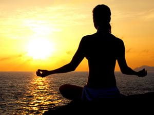 Woman meditating by the ocean