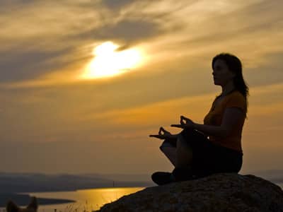 Meditating against an orange sky.