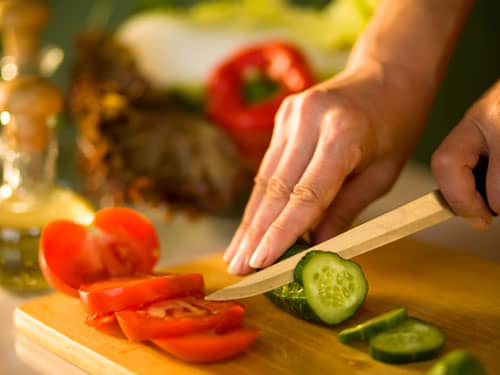 Woman's hand cutting vegetable food with knife