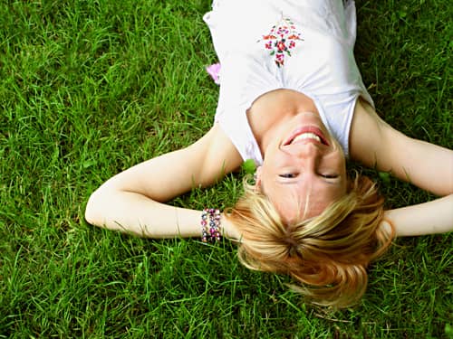 A similing woman lying on a green field