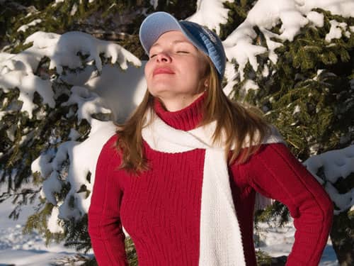 Woman in red taking deep breath in snowy forest