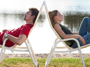 Couple in lawn chairs by lake