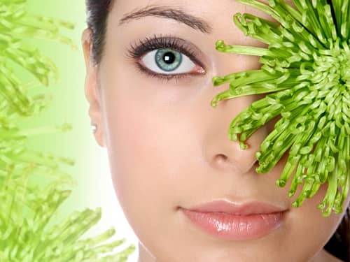 Green-eyed woman hiding behind a flower