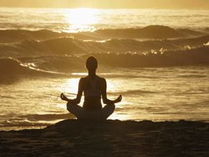 Silhouette of woman meditating on beach