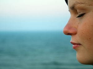 Woman praying and meditating by the ocean