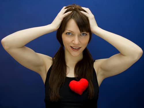 Woman holding head and wearing heart on shirt