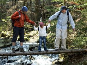 Parents crossing river, holding child between them