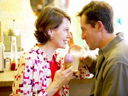 Man drinking milkshake Woman eating ice cream cone on a date