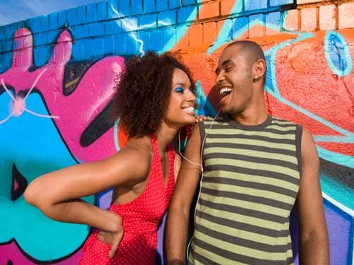 Man and woman laughing against graffiti wall