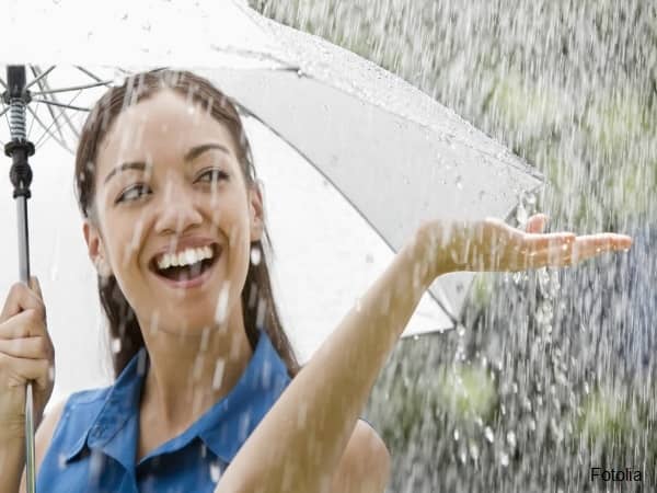 Smiling woman under umbrella in heavy rain